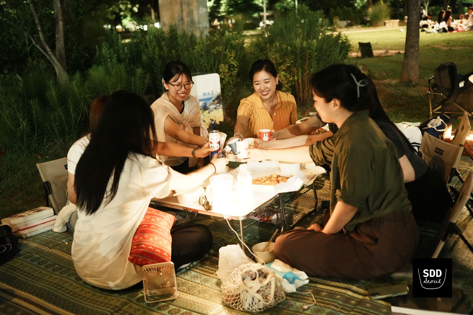 밤, 피크닉 테이블에서 대화하는 참가자들
