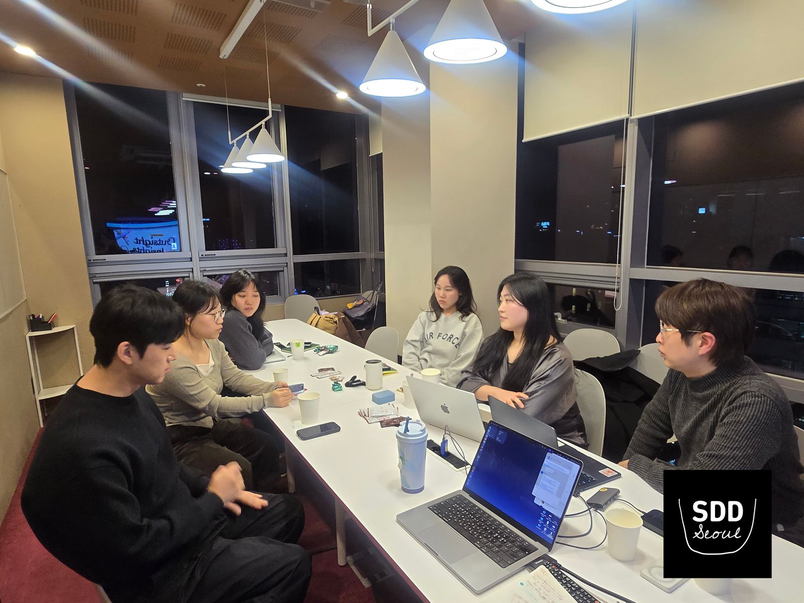 노트북을 펼친 긴 테이블에 둘러앉아 이야기를 나누는 참가자들